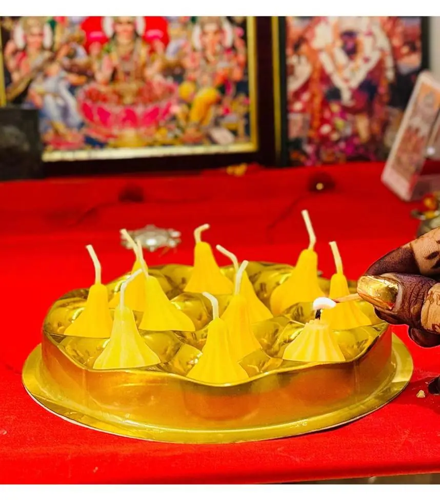 Yellow modak candles lit on a golden thali