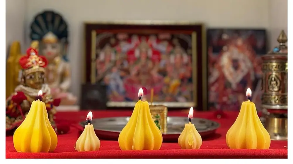 Lit modak candles before a Ganesh shrine