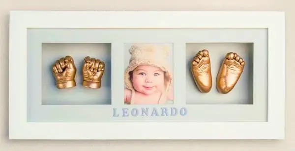 Gold-cast baby hands and feet in a white frame with a portrait